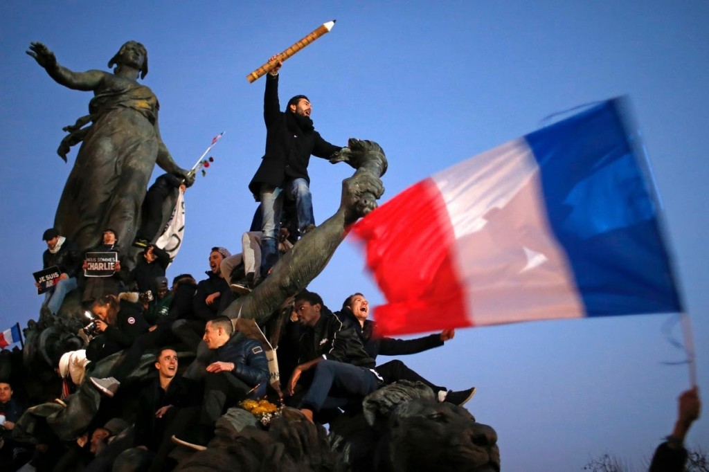 Photo by Stephane Mahe / Reuters: Protesters stand on “The Triumph of the Republic” statue in Paris at a solidarity march for Charlie Hebdo on January 11